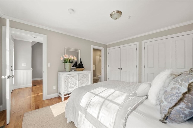 bedroom featuring light wood-style floors, baseboards, ornamental molding, and two closets