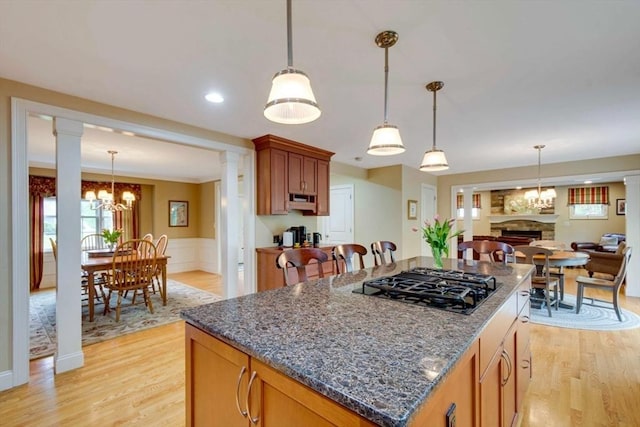 kitchen featuring black gas stovetop, ornate columns, light wood-type flooring, and wainscoting