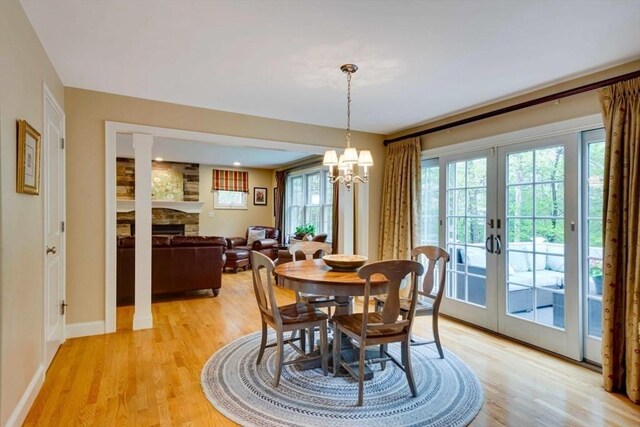 dining area with light wood-style flooring, french doors, baseboards, and a fireplace