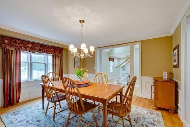 dining room featuring a chandelier, stairway, a wainscoted wall, light wood-style flooring, and ornamental molding