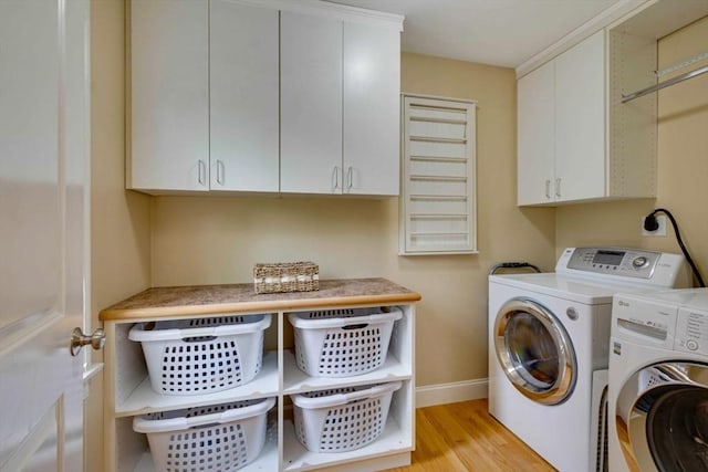 laundry area featuring cabinet space, washer and clothes dryer, light wood finished floors, and baseboards