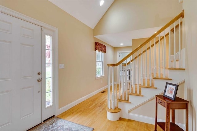 foyer entrance with stairs, wood finished floors, vaulted ceiling, baseboards, and recessed lighting