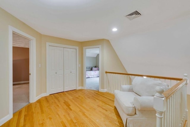 sitting room featuring light wood finished floors, baseboards, an upstairs landing, and vaulted ceiling