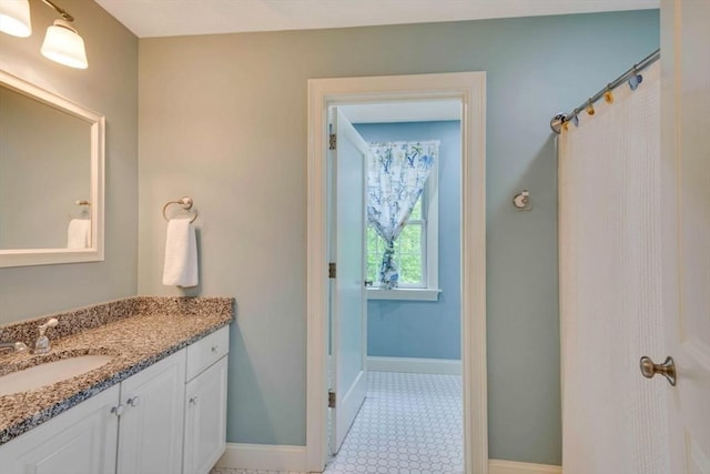 full bath featuring vanity and baseboards