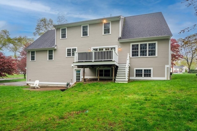 rear view of property with a deck, a shingled roof, and a yard