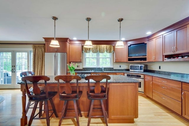 kitchen featuring appliances with stainless steel finishes, a center island, light wood finished floors, french doors, and recessed lighting