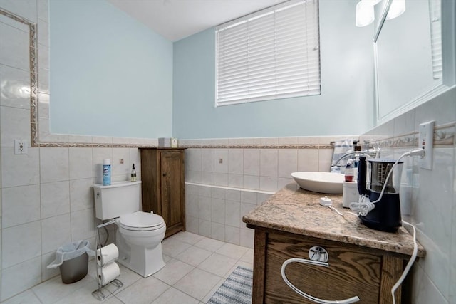 bathroom with tile walls, vanity, toilet, and tile patterned floors