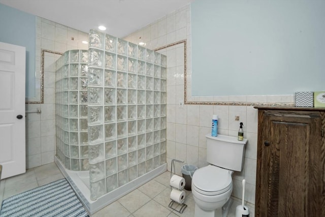 bathroom featuring tile walls, a tile shower, toilet, and tile patterned floors