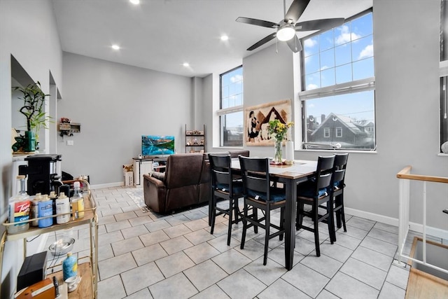 dining room with ceiling fan, light tile patterned floors, and a high ceiling