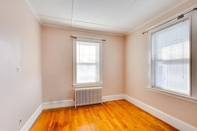 spare room featuring ornamental molding, wood-type flooring, and radiator