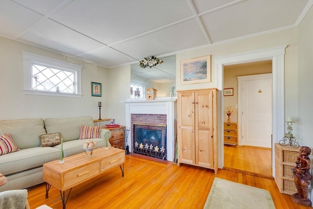 living room featuring coffered ceiling, a fireplace, and light hardwood / wood-style floors