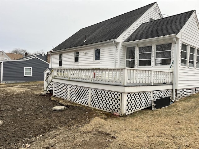 back of house featuring a shingled roof and a wooden deck