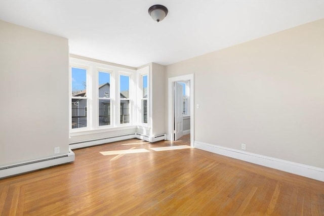 unfurnished room featuring a baseboard radiator, baseboards, baseboard heating, and wood finished floors