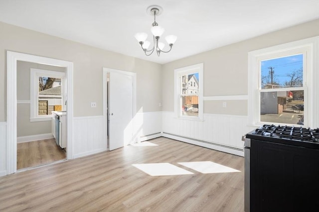 dining space featuring light wood finished floors, a wainscoted wall, a baseboard radiator, baseboard heating, and a notable chandelier