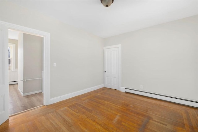 empty room with a baseboard heating unit, baseboards, baseboard heating, and wood finished floors