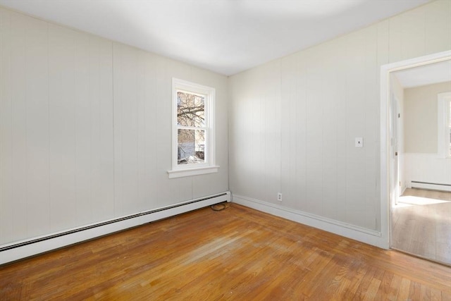 spare room with light wood-type flooring, baseboards, and a baseboard heating unit