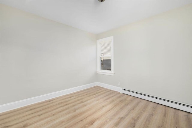 spare room featuring baseboard heating, wood finished floors, and baseboards