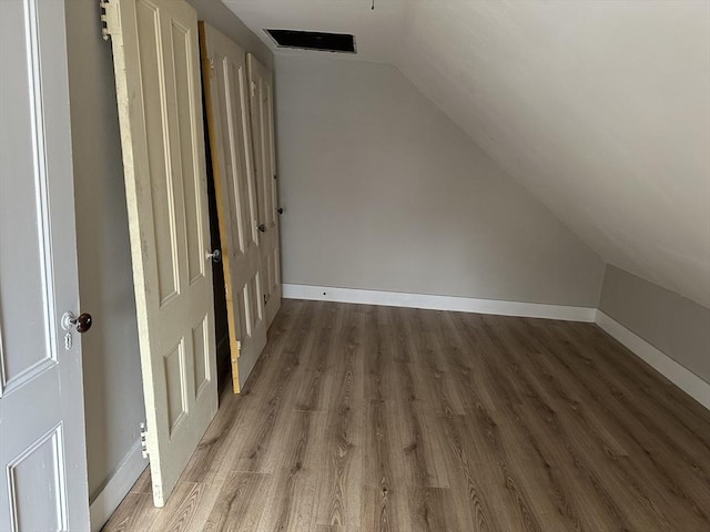 additional living space with vaulted ceiling, baseboards, and wood finished floors