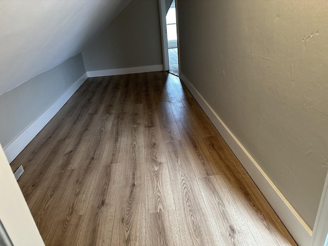 bonus room with lofted ceiling, dark wood-style floors, and baseboards