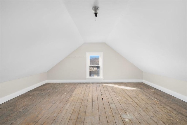 additional living space featuring lofted ceiling, hardwood / wood-style flooring, and baseboards