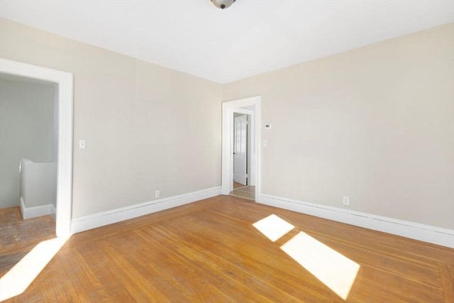 spare room featuring baseboards and wood finished floors