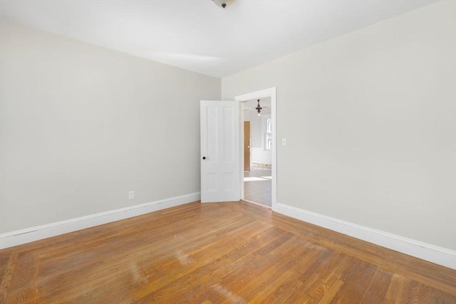 spare room with baseboards and wood finished floors