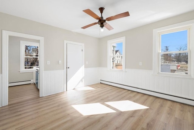 empty room featuring a baseboard radiator, ceiling fan, wood finished floors, and wainscoting