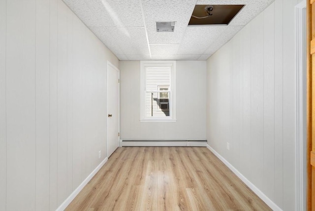 unfurnished room featuring light wood-type flooring, a baseboard radiator, and baseboards