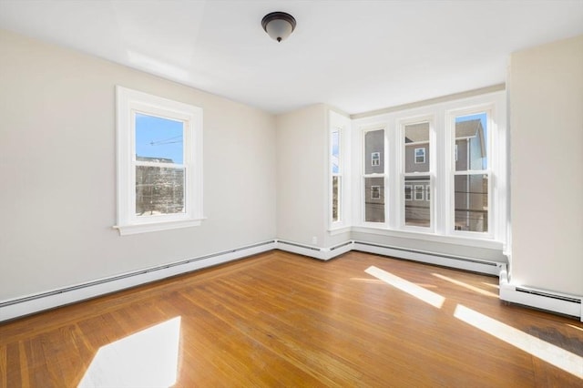 spare room featuring a baseboard heating unit and wood finished floors