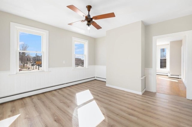 unfurnished room with a baseboard radiator, baseboard heating, wainscoting, ceiling fan, and wood finished floors