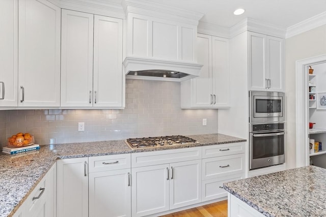 kitchen with stainless steel appliances, light stone countertops, and white cabinetry