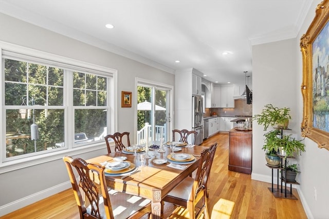 dining room featuring baseboards, light wood-style flooring, and crown molding