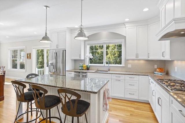 kitchen with custom exhaust hood, a kitchen breakfast bar, appliances with stainless steel finishes, and a sink