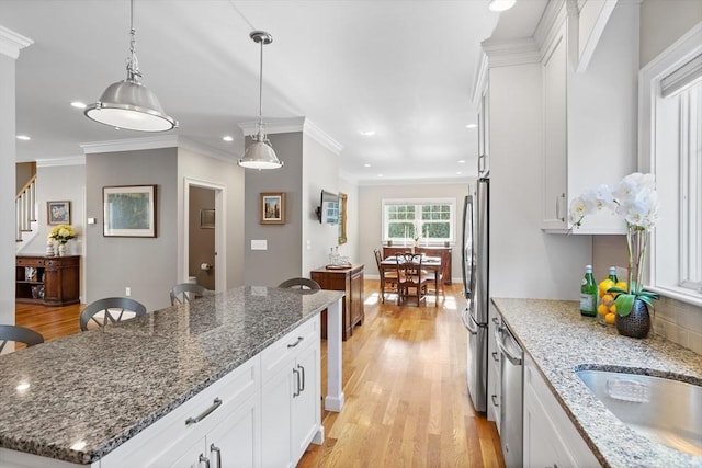 kitchen with stainless steel appliances, white cabinetry, crown molding, and light wood finished floors