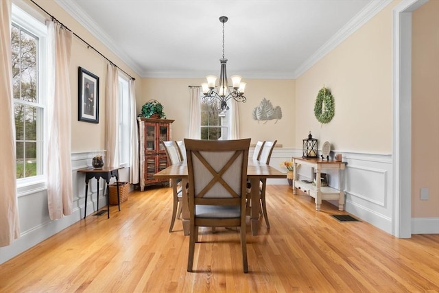 dining room with ornamental molding, visible vents, a chandelier, a wainscoted wall, and light wood-style floors