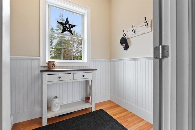 entryway with a wainscoted wall and wood finished floors