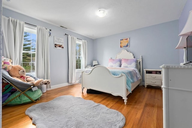bedroom featuring baseboards, visible vents, and wood finished floors