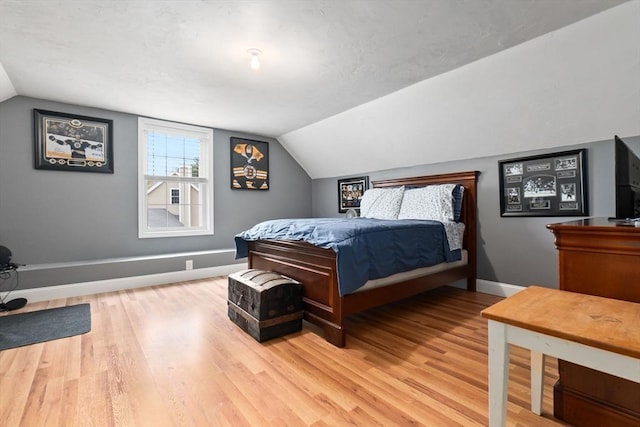bedroom featuring lofted ceiling, baseboards, and light wood-type flooring
