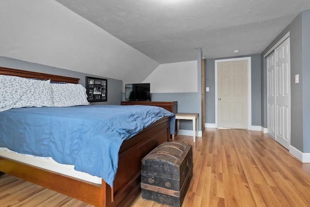 bedroom with wood finished floors, baseboards, and lofted ceiling