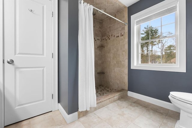 bathroom with toilet, baseboards, a shower stall, and tile patterned flooring