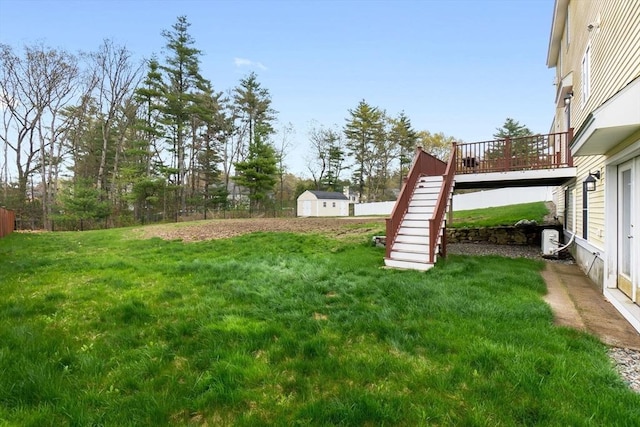 view of yard with fence, a storage unit, an outbuilding, stairway, and a wooden deck