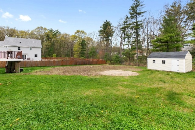 view of yard with fence, a storage shed, a wooden deck, and an outdoor structure