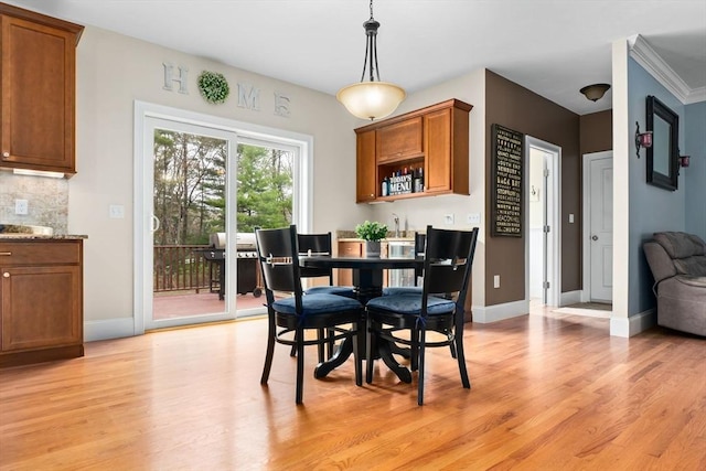 dining space featuring baseboards, light wood-style flooring, and indoor wet bar