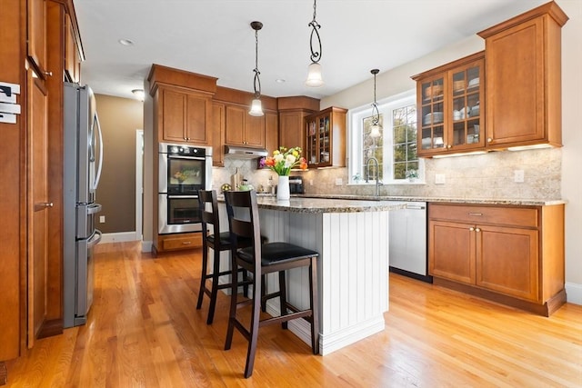 kitchen with light wood-type flooring, brown cabinets, and appliances with stainless steel finishes