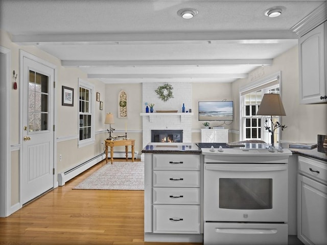 kitchen with dark countertops, beam ceiling, a fireplace, light wood-style floors, and electric stove