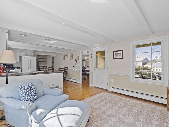 living area featuring a notable chandelier, wood finished floors, baseboard heating, and beam ceiling