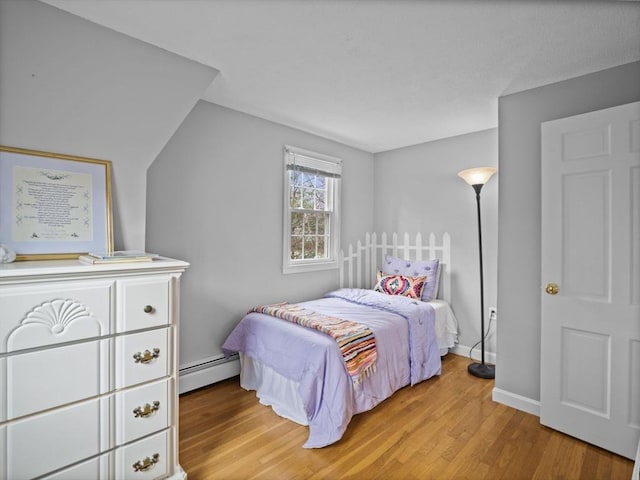 bedroom with baseboards, baseboard heating, and light wood finished floors