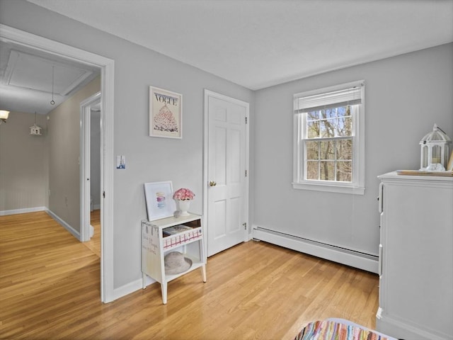 interior space with baseboards, light wood finished floors, baseboard heating, and attic access