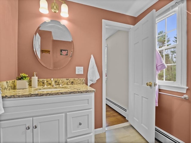 bathroom featuring vanity, baseboard heating, and a wealth of natural light