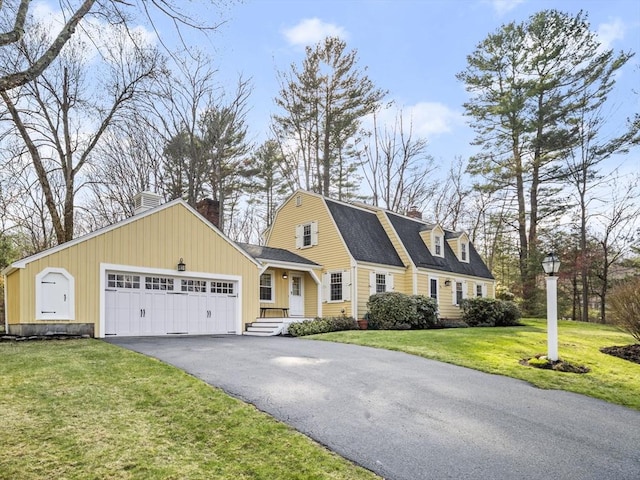 view of front of home featuring a garage, a chimney, driveway, and a front lawn